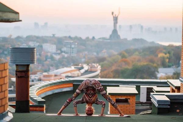 Kvinde laver yoga på taget af en skyskraber i storbyen . - Stock-foto