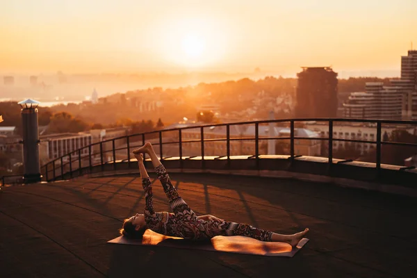 Mujer haciendo yoga en el techo de un rascacielos en la gran ciudad . —  Fotos de Stock