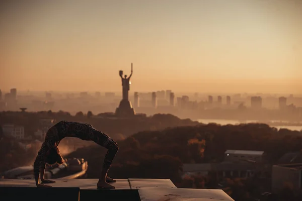 Mujer haciendo yoga en el techo de un rascacielos en la gran ciudad . — Foto de Stock