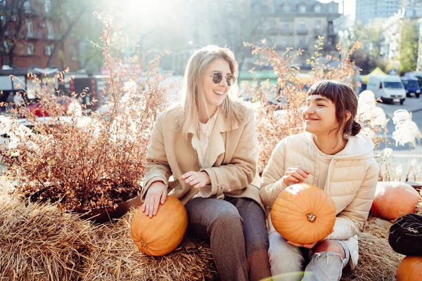 Girls holds pumpkins in hands on the background of the street. — Stok fotoğraf