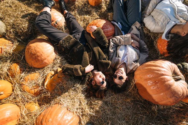 Young girls lie on haystacks among pumpkins. View from above — Stockfoto