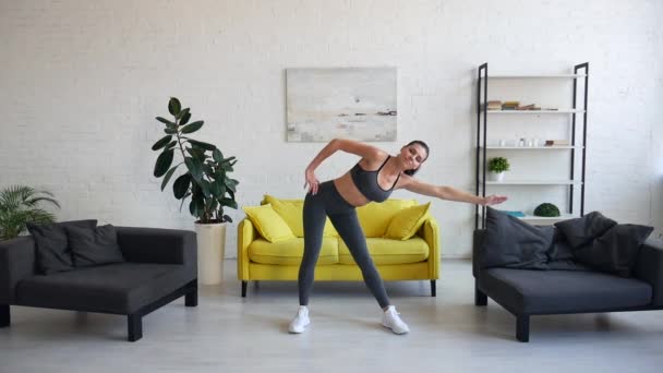 Kaunis nuori nainen tekee vatsan harjoituksia huoneessa — kuvapankkivideo