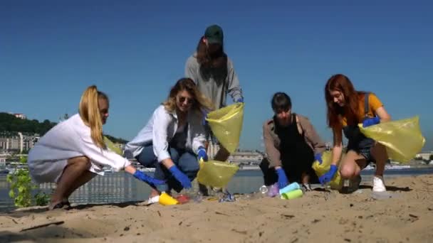 Bir grup aktivist arkadaş plajda plastik atık topluyor. Çevresel koruma. — Stok video