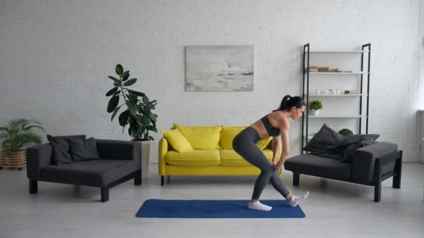 Beautiful young woman does exercises for the abdomen on the rug in the room — Stock Video