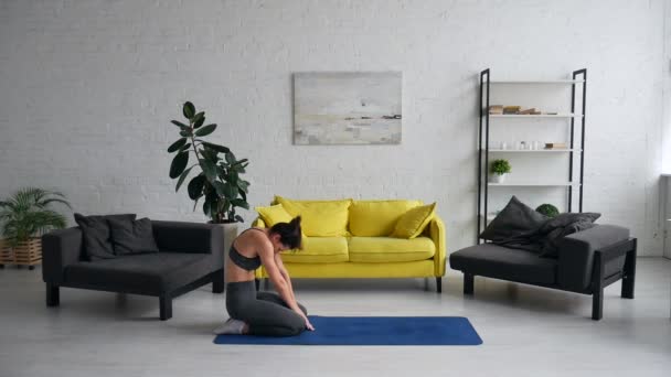 Красива молода жінка робить вправи для живота на килимку в кімнаті — стокове відео