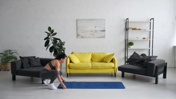 Beautiful young woman does exercises for the abdomen on the rug in the room — Stock Video