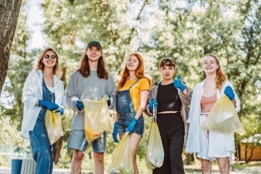Bir grup aktivist arkadaş parkta plastik atık topluyor. Çevresel koruma.