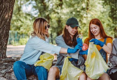 Bir grup aktivist arkadaş parkta plastik atık topluyor. Çevresel koruma.