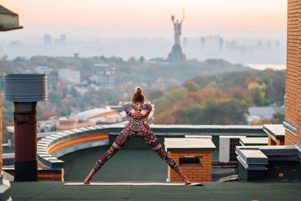 Mujer haciendo yoga en el techo de un rascacielos en la gran ciudad . —  Fotos de Stock