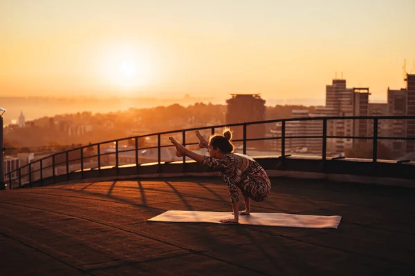 Mujer haciendo yoga en el techo de un rascacielos en la gran ciudad . —  Fotos de Stock