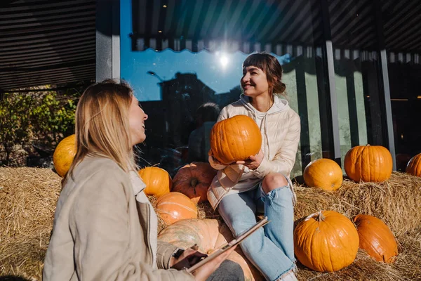 Girls have fun among pumpkins and haystacks on a city street — Stock Photo, Image