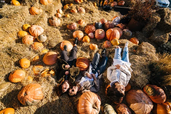 Las chicas jóvenes yacen en un pajar entre calabazas. Vista desde arriba — Foto de Stock