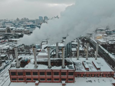 Kocaman boruları olan büyük merkezi kazan dairesi. Büyük bir şehirde kış ayazları sırasında tehlikeli dumanlar çıkıyor.