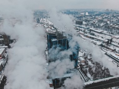 Kocaman boruları olan büyük merkezi kazan dairesi. Büyük bir şehirde kış ayazları sırasında tehlikeli dumanlar çıkıyor.