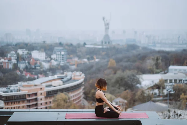 Mujer practicando yoga en la esterilla en el techo y haciendo ejercicios de yoga —  Fotos de Stock