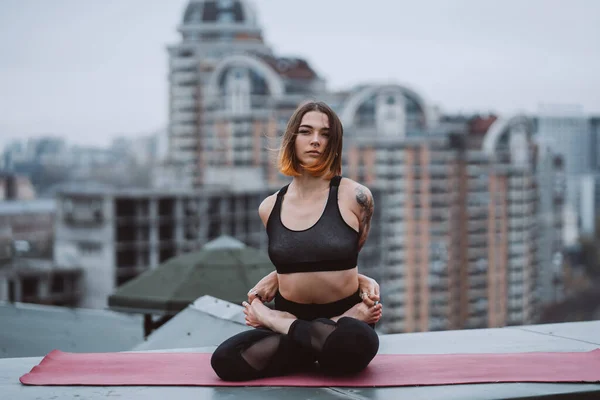 Mujer practicando yoga en la esterilla en el techo y haciendo ejercicios de yoga —  Fotos de Stock