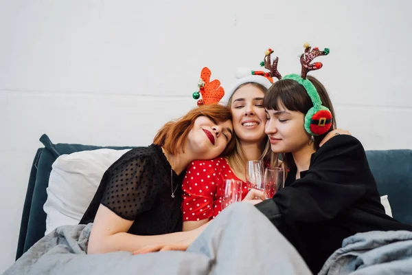 Sonrientes modelos femeninas sosteniendo copas de vino y disfrutando de la fiesta de pijamas. — Foto de Stock