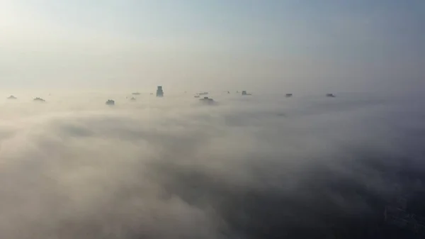 Flygfoto över staden i dimman. Skyskrapor ovanför dimman — Stockfoto