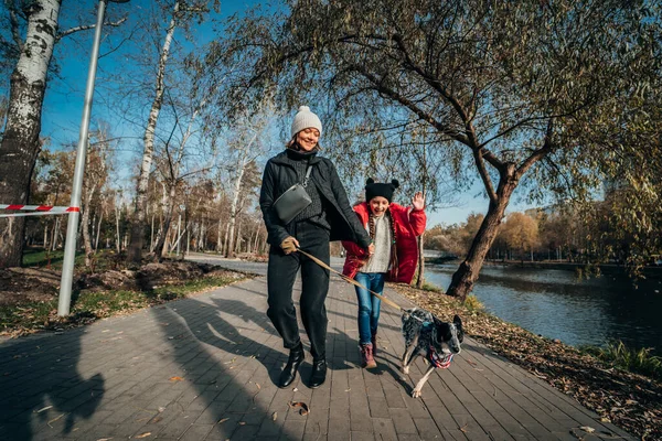 Lycklig mamma och hennes dotter leker med hunden i höstparken — Stockfoto