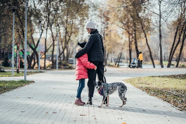 Feliz madre y su hija pasean con el perro en el parque de otoño — Foto de Stock
