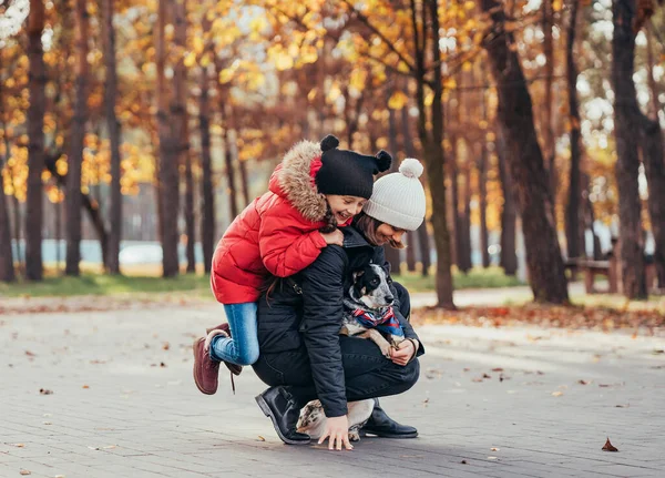 Felice madre e sua figlia a giocare con il cane nel parco autunnale — Foto Stock