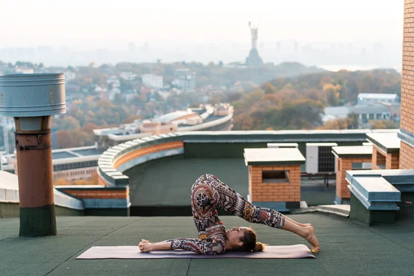 Mujer haciendo yoga en el techo de un rascacielos en la gran ciudad . —  Fotos de Stock