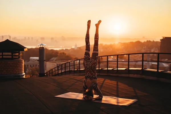 Mujer haciendo yoga en el techo de un rascacielos en la gran ciudad . —  Fotos de Stock