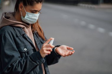 Beyaz kız ellerini dezenfekte edici spreyle dezenfekte ediyor..