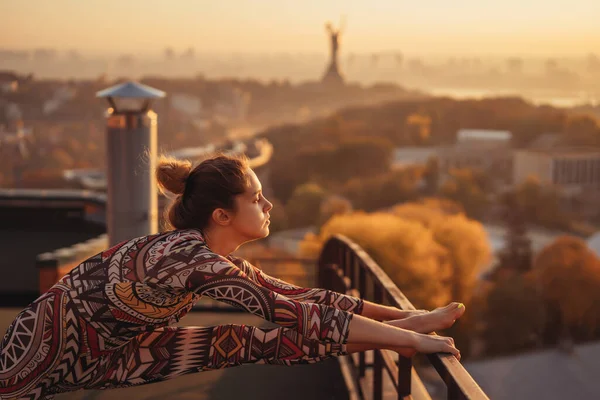 Vrouw doet yoga op het dak van een wolkenkrabber in de grote stad. — Stockfoto