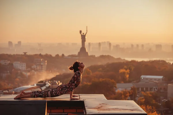 Mujer haciendo yoga en el techo de un rascacielos en la gran ciudad . —  Fotos de Stock