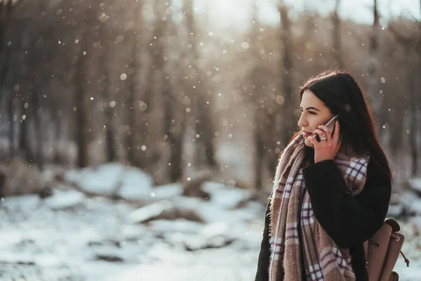 Kvinnan pratar i mobilen. Leende flicka talar på mobiltelefon i kall vinterdag. — Stockfoto
