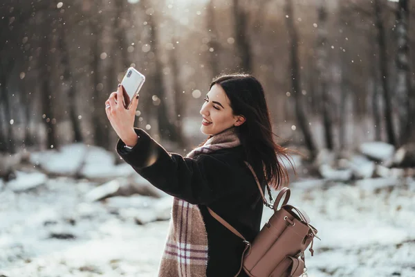 Feliz sorrindo adolescente ou jovem mulher tomando selfie por smartphone no parque de inverno — Fotografia de Stock
