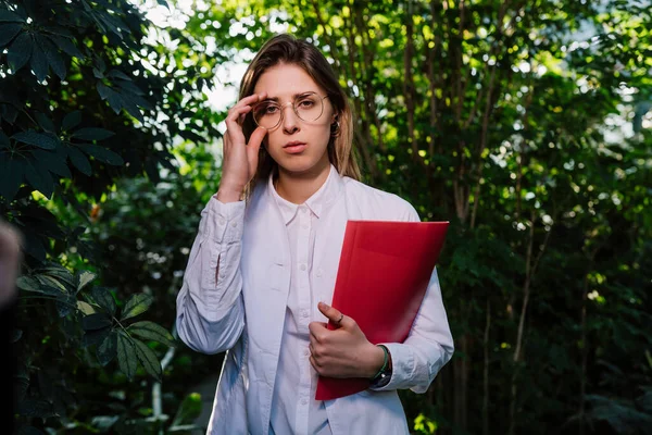 Young agricultural engineer working in greenhouse. Young female scientist looking at the camera — Stock Photo, Image