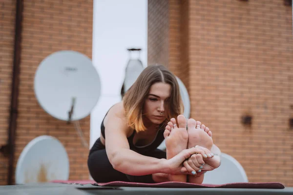 Mujer practicando yoga en la esterilla en el techo y haciendo ejercicios de yoga —  Fotos de Stock