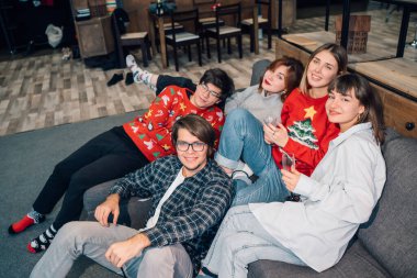 Grup arkadaşları oturma odasında bir kanepede oturuyor.