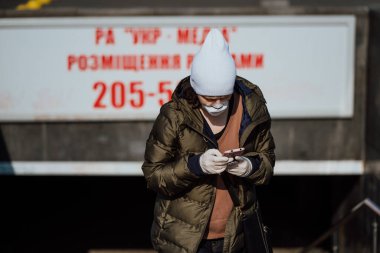 Kiev, Ukrayna, 28 Mart 2020 'de elinde telefonla metrodan çıkan bir kadın.