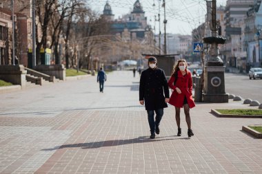 Kiev, Ukrayna, 28 Mart 2020 Ukraynalılar, Ukrayna 'da neredeyse boş bir sokakta yüz koruma maskesi takıyorlar.,