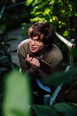 Çalılıklarda saklanan erkek bilim adamı. Doğa koruma kavramı.