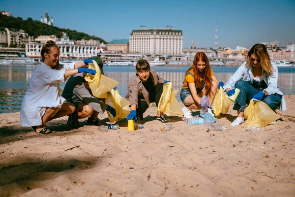 Grupo de activistas amigos recogiendo residuos plásticos en la playa. Conservación ambiental . — Foto de Stock