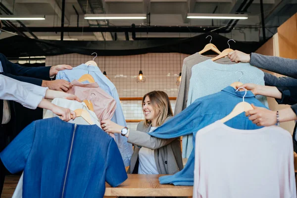 Mladý stylista hledá přes sadu košil pro módní natáčení — Stock fotografie