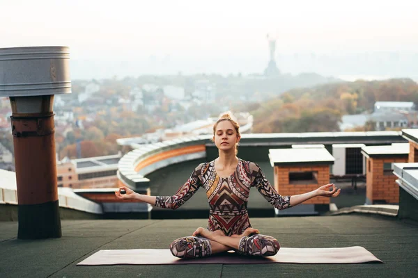 Žena, která dělá jógu na střeše mrakodrapu ve velkém městě. — Stock fotografie