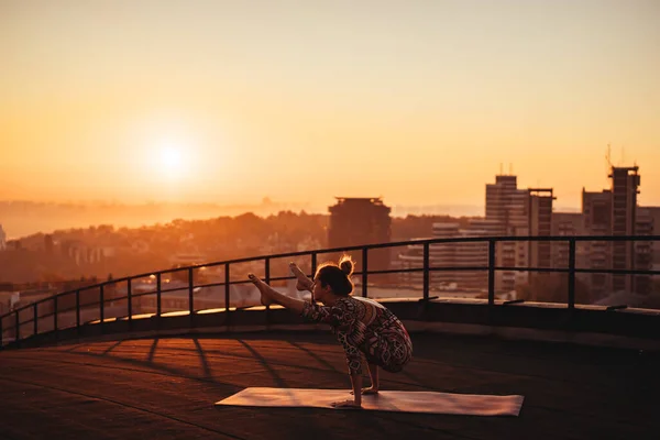 Mujer haciendo yoga en el techo de un rascacielos en la gran ciudad . —  Fotos de Stock