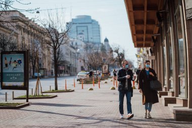 Kiev, Ukrayna, 28 Mart 2020 Ukraynalılar, Ukrayna 'da neredeyse boş bir sokakta yüz koruma maskesi takıyorlar.,