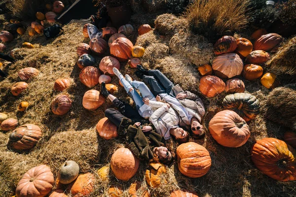 Young girls lie on haystacks among pumpkins. View from above — Stock Photo, Image