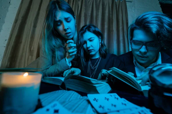 Dos mujeres y un hombre están leyendo libros misteriosos, de cerca —  Fotos de Stock