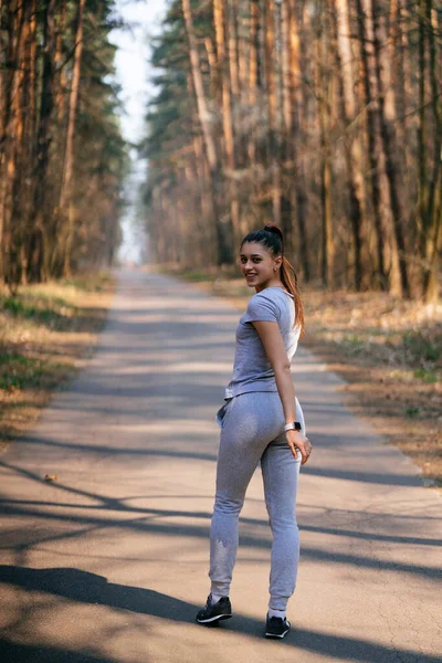 フィットネス若い女性が公園を歩き、カメラのためにポーズ — ストック写真