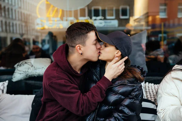 Guy e uma menina estão se beijando em uma mesa em um café ao ar livre. — Fotografia de Stock