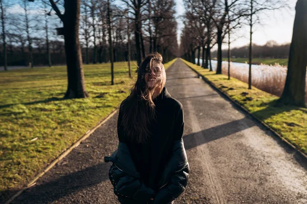 Porträtt av en brunett flicka som har roligt i en park i solens strålar. — Stockfoto