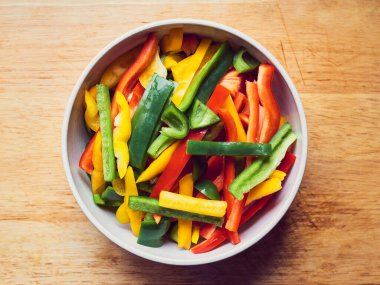 Kırmızı biber, yeşil biber ve ahşap masada sarı biber.