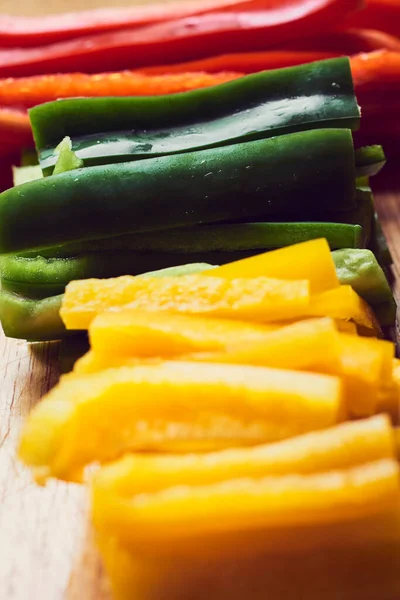 Kırmızı biber, yeşil biber ve ahşap masada sarı biber.